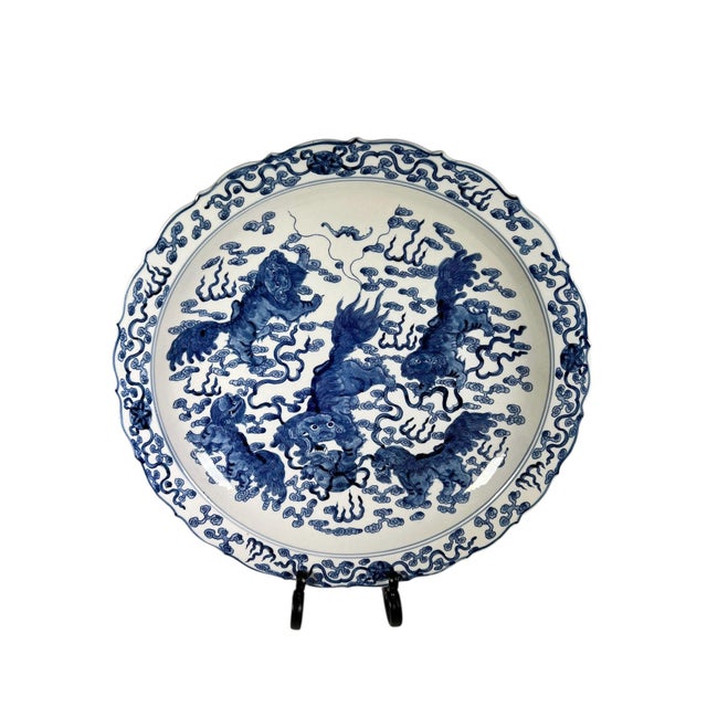 A striking pair of Chinese blue and white painted chargers, each featuring beautifully stylized foo dogs and delicate...