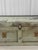 A flat-top wood trunk, circa 1940s, in its original sage green over off-white paint, crackled and chipped down to bare...