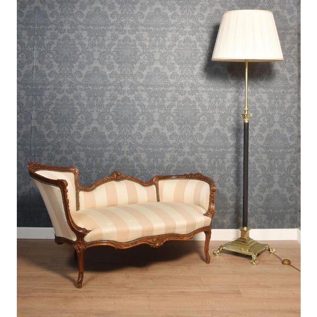 Walnut framed two-seater settee, the finely carved frame above upholstered back, seat and out swept arms. All raised up on...