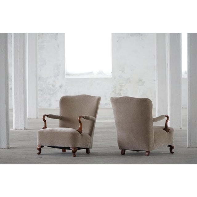 A pair of elegant antique early 20th century lounge chairs executed in a style reminiscent of the Victorian period, made...