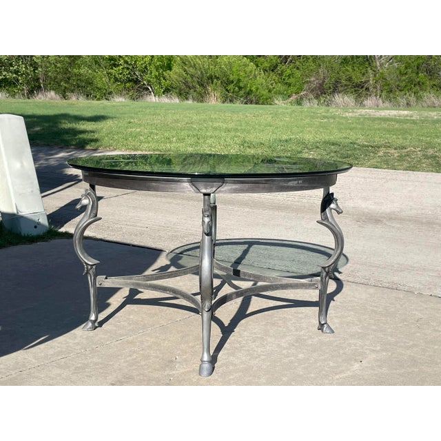 modern classic with a sculptural twist — this round center table features a cast steel base with four stylized horse...