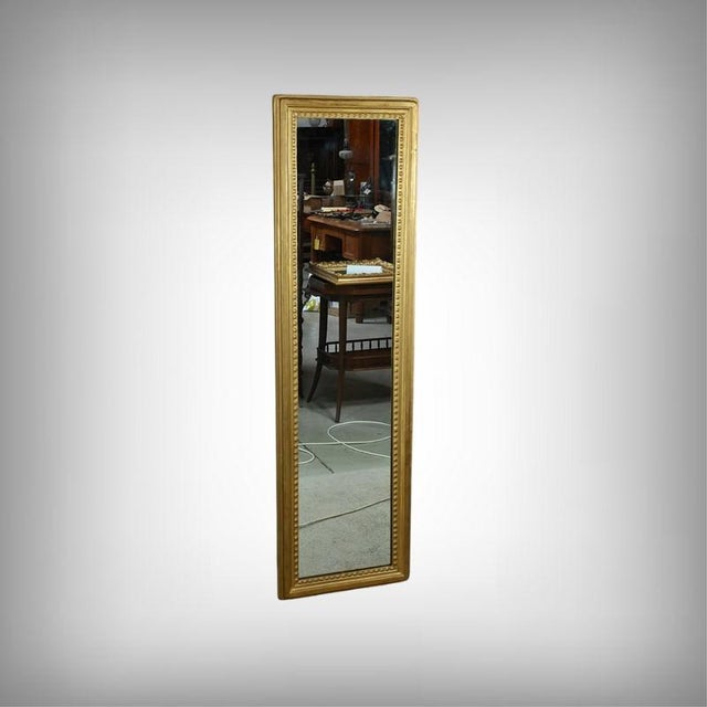 This gilt-leaf wood mirror elegantly embodies the refinement of the Louis XVI style. Its slender, rectangular shape...