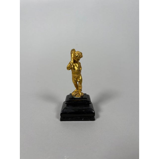 A 17th-century bronze sculpture of the infant Hercules, chased and gilded. He is depicted standing, holding his club over...