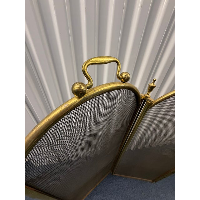 This antique brass fireplace screen features a classic four‑panel folding design with arched tops, fine mesh panels, and...