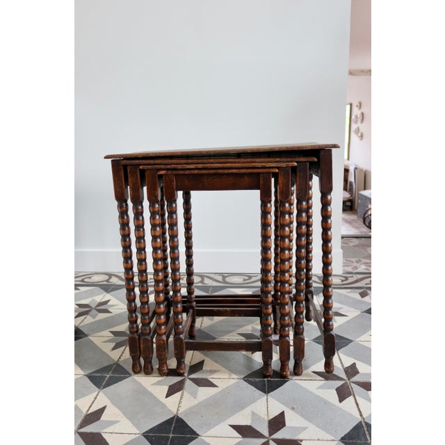Set of four antique nesting tables in dark wood with turned legs, in an English, family home style. Their slender...