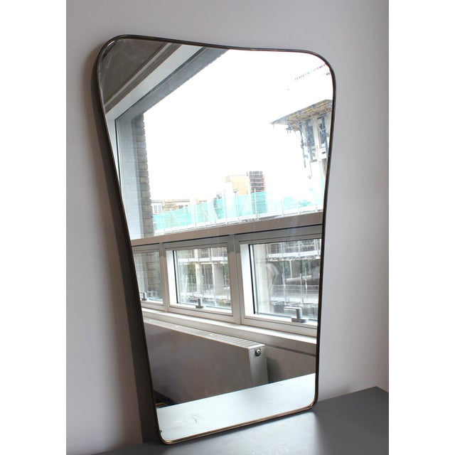 Mid-century italian wall mirror with brass frame (circa 1960s). The mirror is classically-shaped and certainly modern in...