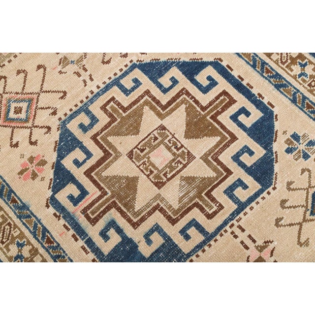 This hand-knotted Caucasian Kazak runner features bold geometric medallions in earthy and navy tones. A timeless piece to...