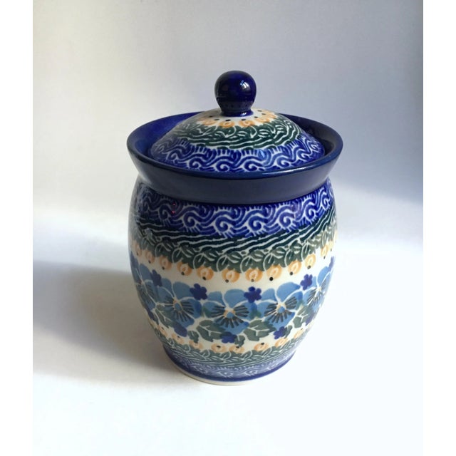 Maria Starzyk Painted Pansy Ceramic Canister. Featuring a hand painted glazed pottery flared White jar form with domed...