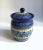 Maria Starzyk Painted Pansy Ceramic Canister. Featuring a hand painted glazed pottery flared White jar form with domed...