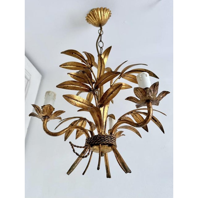 French gilt tole chandelier featuring hand-formed palm and botanical leaves arranged around three scrolling candle arms....