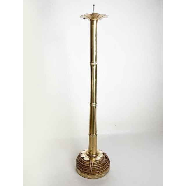 French floor candle holder dating from the 1970s, crafted from brass and rattan. Its tall, slender structure evokes a...