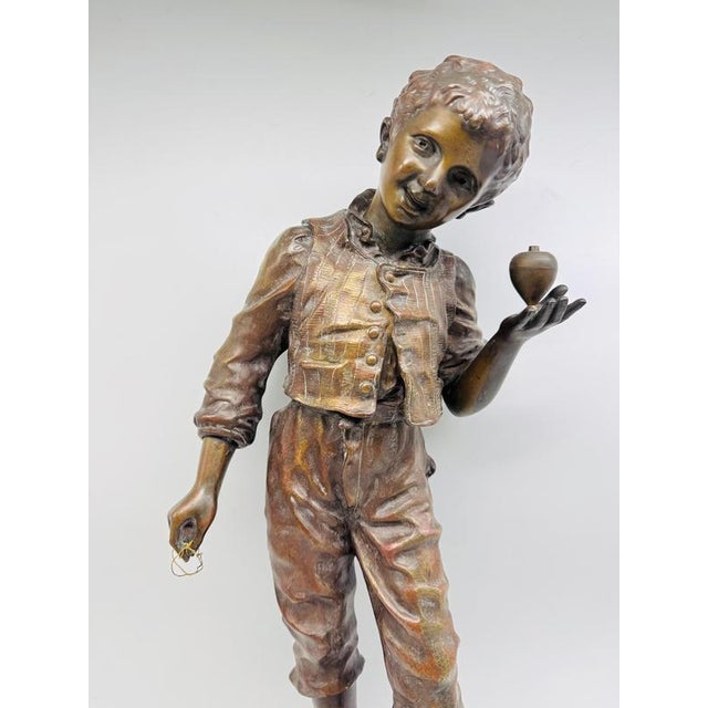 The sculpture is an antique, patinated bronze figure entitled "Elle ronfle" (She Snores) by the 19th-century French...