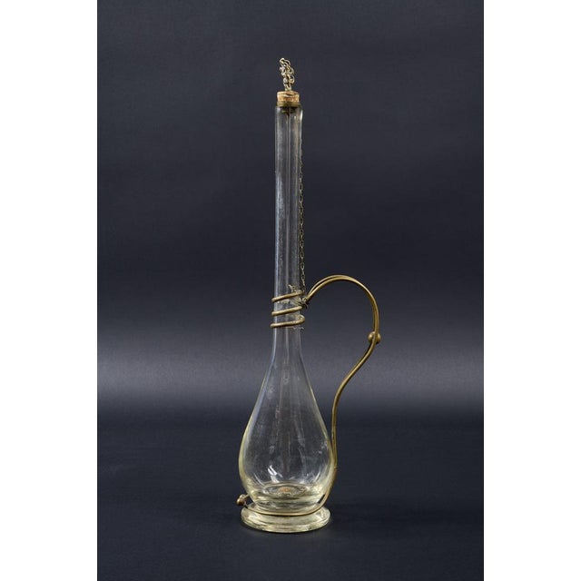 Beautiful blown glass decanter bottle. It features elegant brass appliqués representing a snake on the body and an...