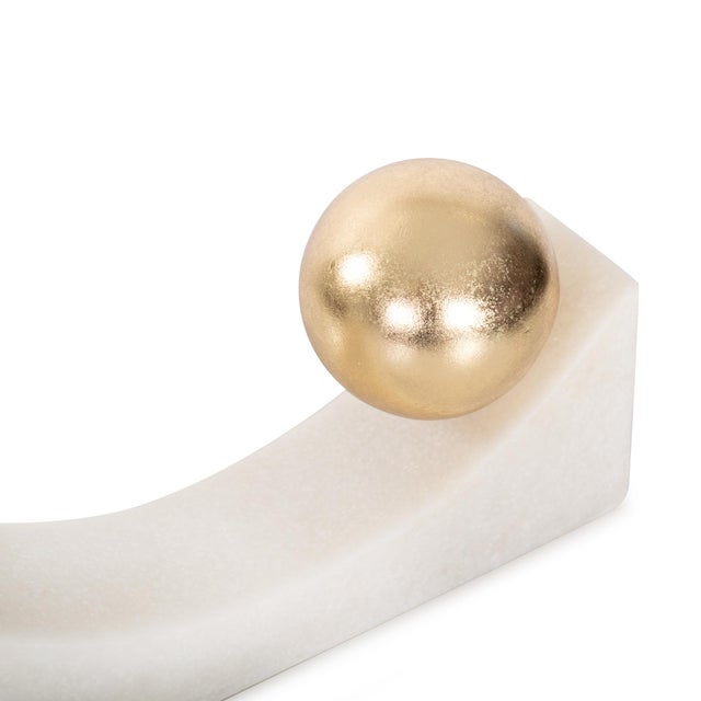 Modern and sculptural, these geometric figures feature white stone bases with striking gold spheres. A bold statement for...