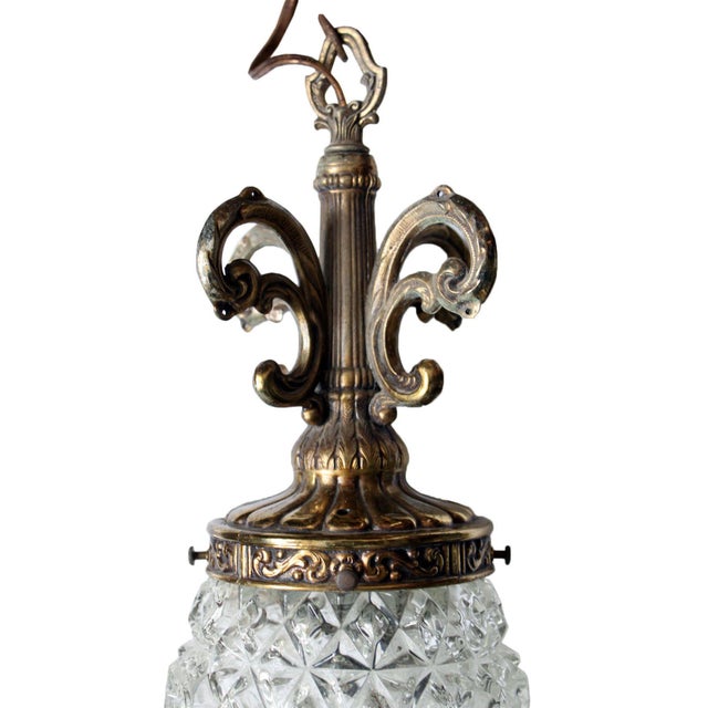 Experience the timeless allure of a mid-century Hollywood regency brass pendant, featuring a clear cut glass pineapple....