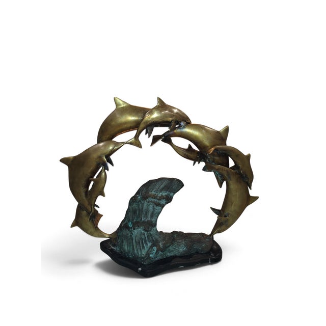 Vintage patinated bronze sculpture depicting a pod of dolphins leaping in a circular formation. Artist unknown