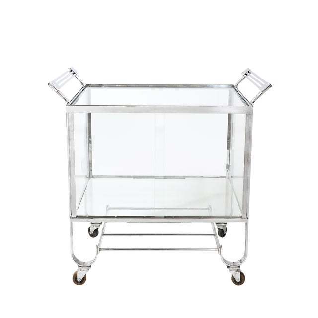 An exceptional Art Deco two-tier rolling bar/serving cart, designed by Treitel & Gratz, featuring a refined glass door...