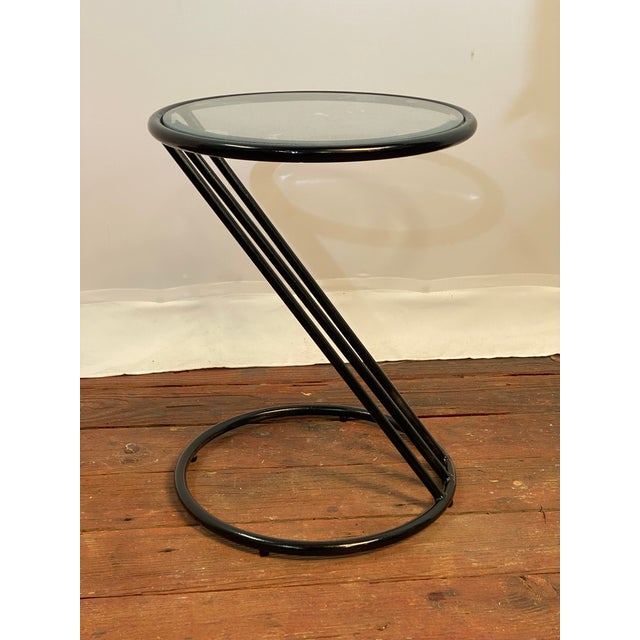 Tubular metal 'Z' shaped frame with a round glass top. Small, compact, minimalist design.Glossy black finish. Circa...