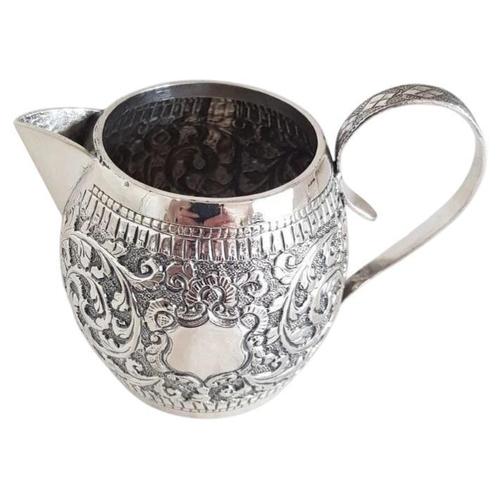 A distinctive late 19th-century high-grade silver cream jug, displaying richly worked decoration associated with Persian,...