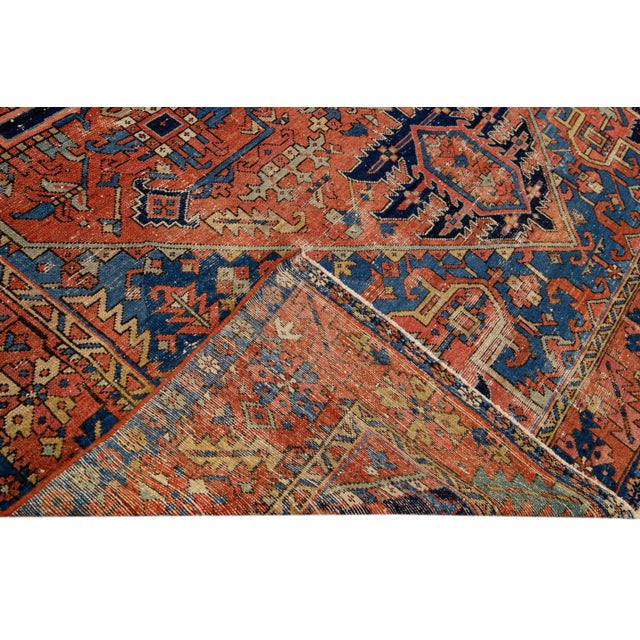 Beautiful antique Heriz hand-knotted wool rug with a rust field. This Persian rug has navy-blue, brown, and beige accents...