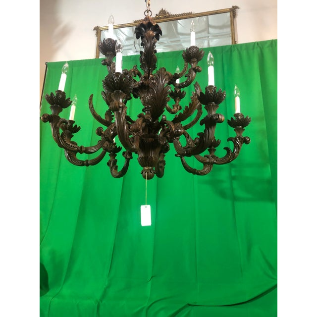 Beautiful hand carved 2 tier chandelier with 12 lights featuring a scrolled acanthus leaf design in walnut finish. Italy