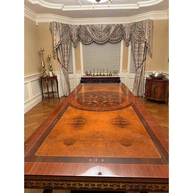A large, rectangular mahogany dining table with decorative gold-tone or ormolu mounts along the apron and double pedestal...