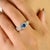 This elegant halo ring showcases an oval-cut blue sapphire weighing approximately 0.66 carats, elegantly set in rich 14K...
