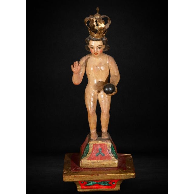 A charming 17th-century Colonial sculpture depicting the Niño Jesús as Salvator Mundi, carved in wood and retaining its...