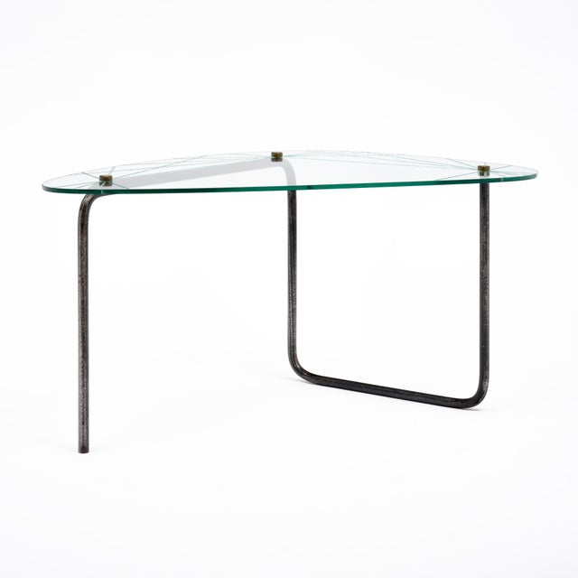 Coffee table from the mid-century period in France. This piece has a glass top in a curved triangular shape. The table has...