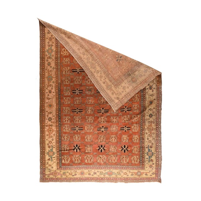 The rust field of this rustic Central Asian piece shows a seven by thirteen arrangement of repeating stylized flowers and...