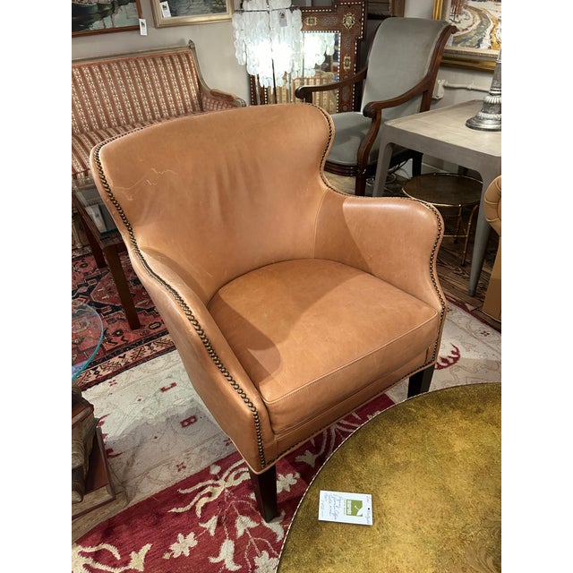 Leather club chairs having a beautiful compact and comfortable silhouette, finished with brass nailheads. Some minor...