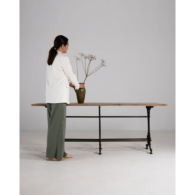 This piece presents as a bench/table, distinguished by black wrought iron base, natural wood top. Dating to 1900s and...
