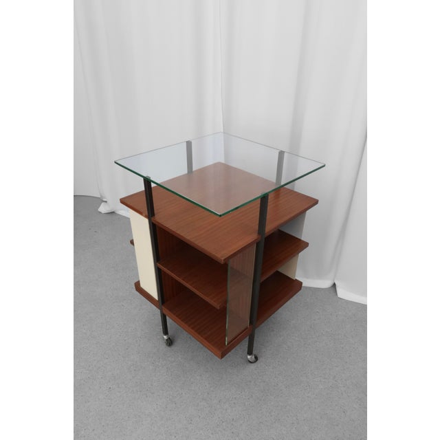 Serving trolley from the 1950s in mid-century style. Glass top, wooden shelves and dark grey metal construction on wheels....