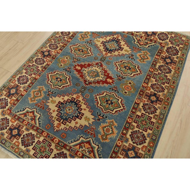 This traditional tribal geometric Caucasian Kazak rug is hand-knotted with an all-wool pile on a cotton foundation. This...