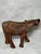Decorative hand-carved wooden buffalo figurine. The textured surface and simplified, organic form indicate traditional...