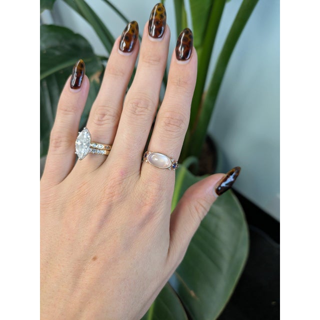 A 3.00-carat rainbow moonstone cabochon sits at the centre of this solid 14K rose gold ring, framed by eight earth-mined...