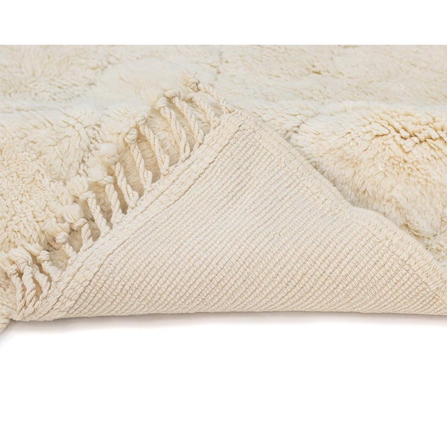 Minimalist hand-knotted natural wool rug showcasing a delicate Ivory tone with an intricate array of asymmetrical...