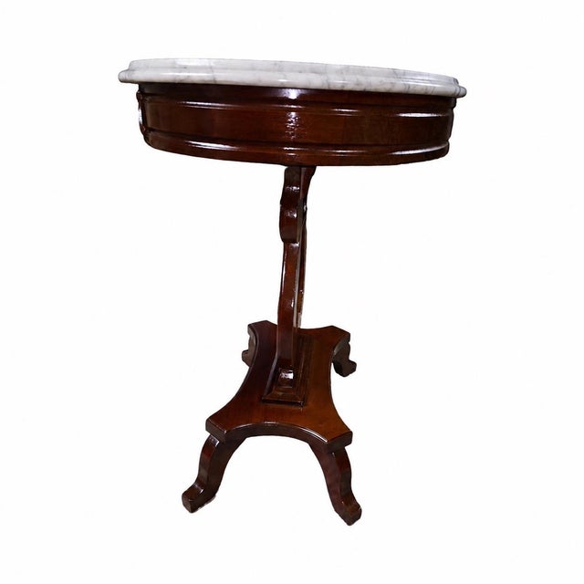 An elegant vintage Neoclassical-style accent table featuring a substantial round white marble top supported by an...