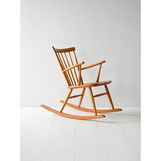 Vintage rocking chair from the 1950s and 1960s with a solid beech frame, a contoured teak seat, and a thin spoked...