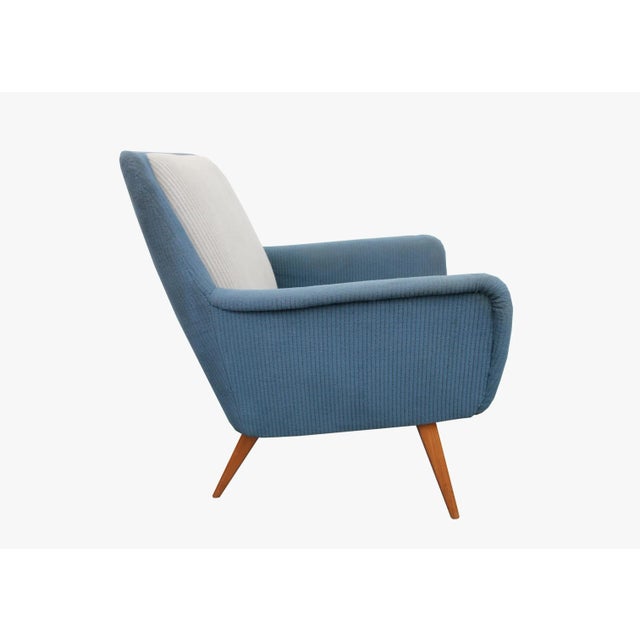 This armchair features inclined legs made of solid cherry. It remains in its original cover and cushions in two colours.