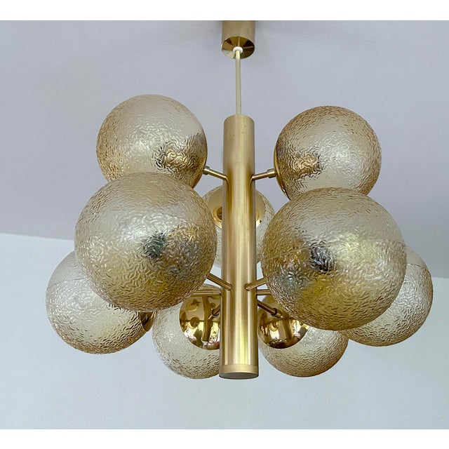 very large mid century pendant light, brass structure with 9 radiating beams and large amber tint structured glass globe...