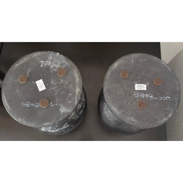 A striking pair of solid black marble covered vessels, hand-carved with graceful acorn-inspired silhouettes. Each vessel...