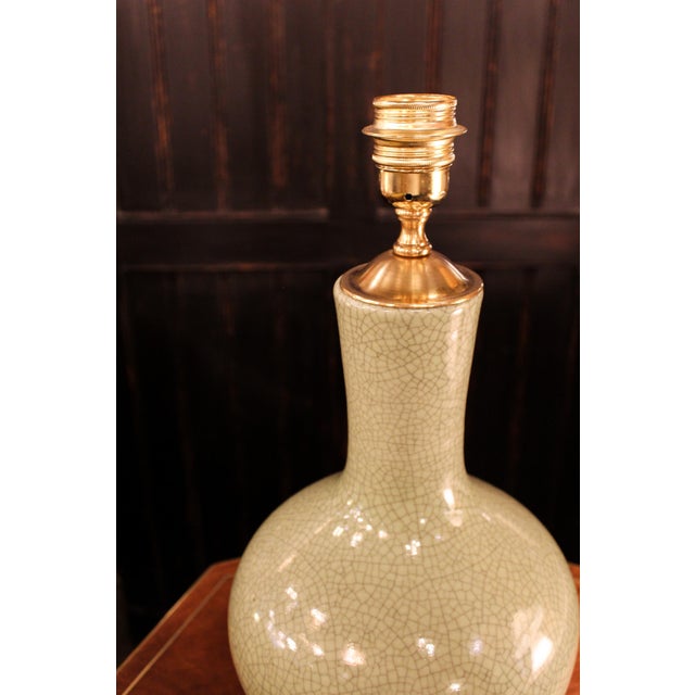 A glazed ceramic table lamp with a celadon green crackle finish. Its surface reveals a delicate network of fine cracks...