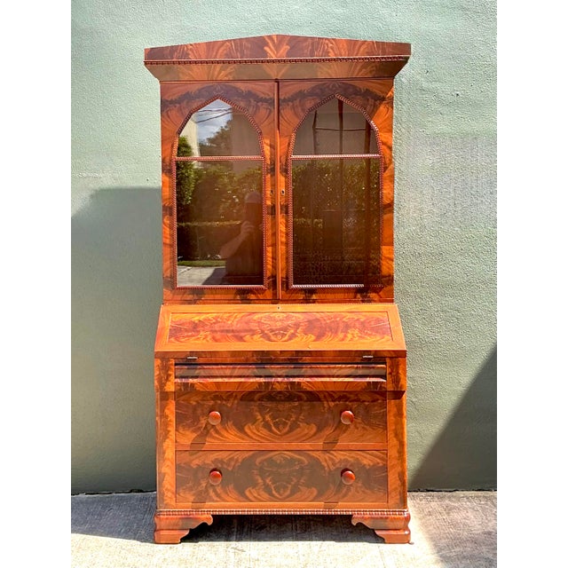 This magnificent Empire-style secretary desk is a masterclass in 19th-century cabinetmaking, featuring spectacular book-...