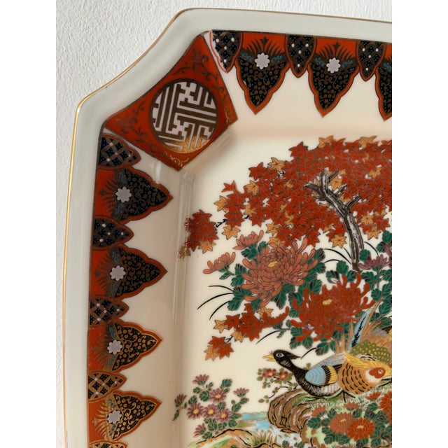 Large porcelain plate with peacocks and chrysanthemums. Painted with detailed japanese symbols and shapes. Orange, red,...