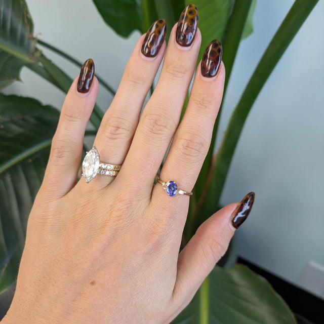 A 0.95-carat blue tanzanite oval sits at the centre of this solid 14K rose gold ring, framed by three earth-mined...