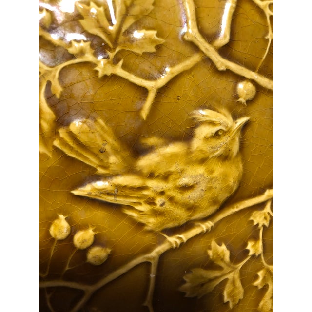 Antique Tile. Bird on Branch. Dark Mustard color. Chip of bottom left corner. Surface wear on bird with crazing on tile....