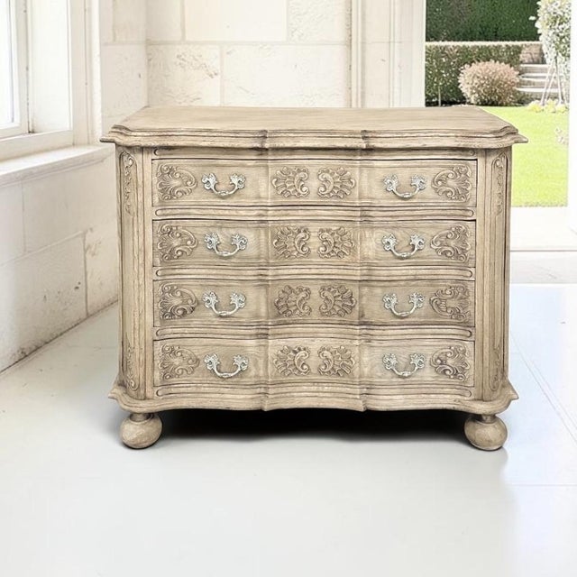 A French Louis XIV commode in stripped oak, with a serpentine facade carved in shell, floral and foliate motifs that flow...