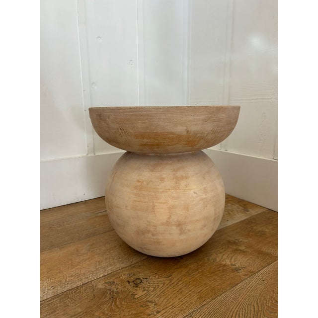 Hand-formed terracotta stool or side table with a rounded base and flat top. Natural matte finish with subtle tonal...