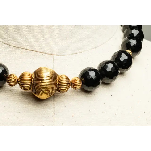 An amazing beaded necklace of large, faceted black onyx beads with five graduated melon-shaped 22K gold beads featured at...